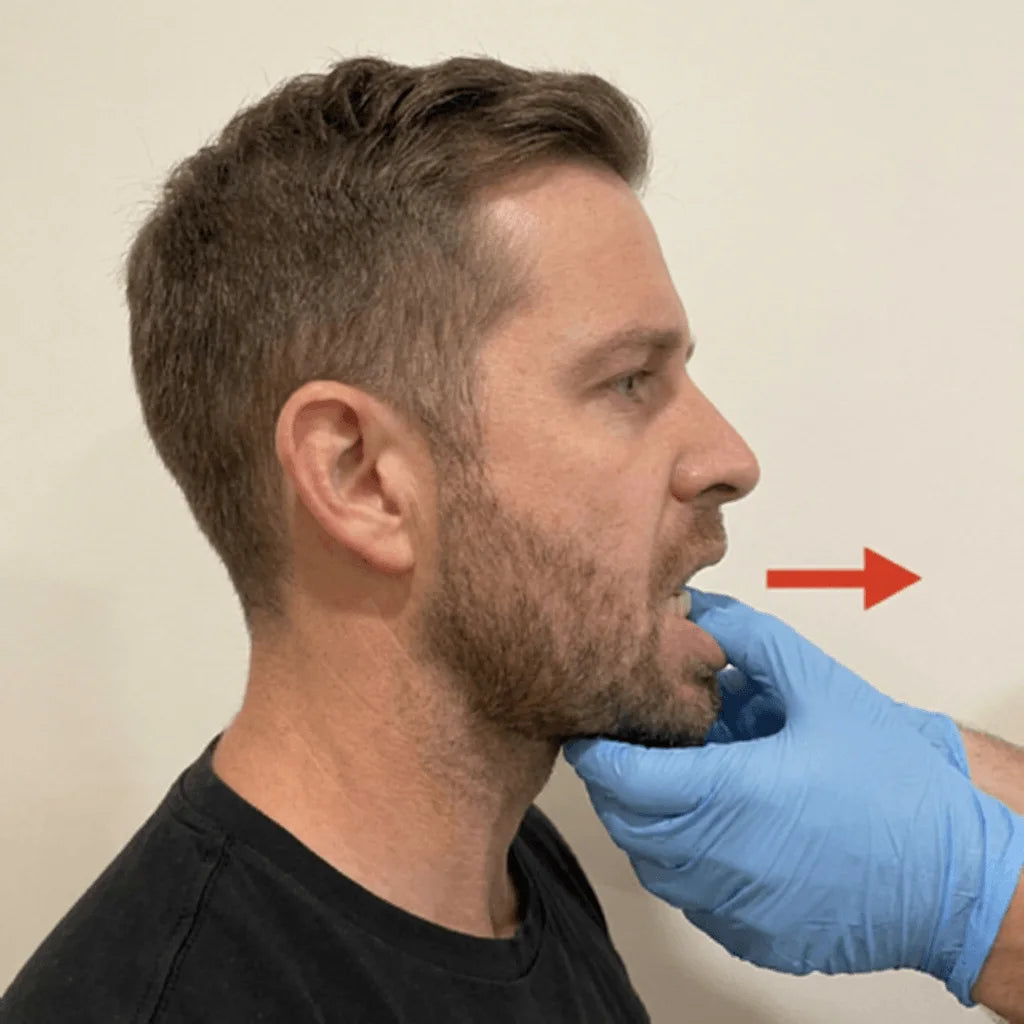 Side profile of a man with a clinician's gloved hand gently advancing his lower jaw forward — red arrow indicates the forward motion that opens the airway